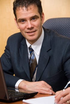 Businessman in a board room with his grey laptop