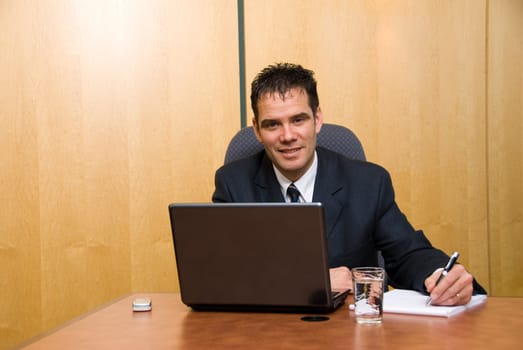 Businessman in a board room with his grey laptop