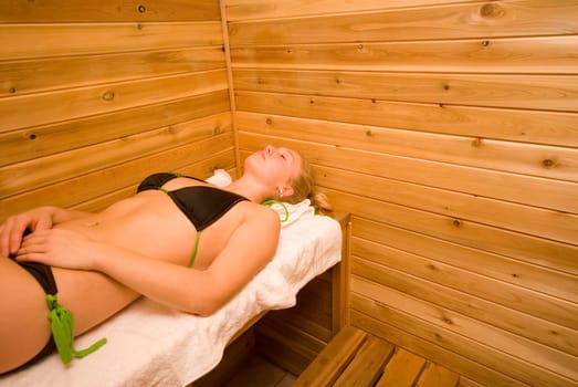 blond woman sleeping in the wood sauna