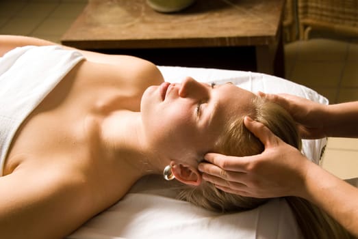 woman in a day spa getting a head massage by therapist
