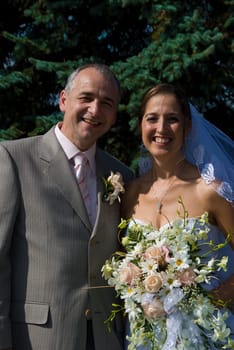 a bride and a groom posing behind some trees