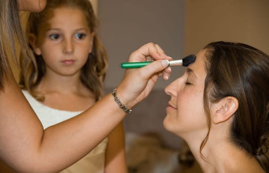 The bride getting her makeup done before her wedding