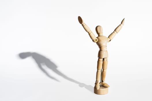 Happy wooden mannequin with sad shadow isolated in white background.