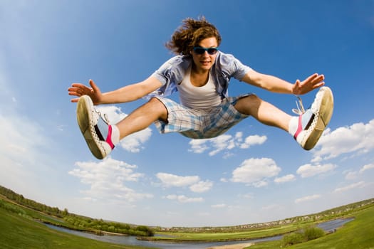 Portrait of energetic man jumping high against bright blue sky