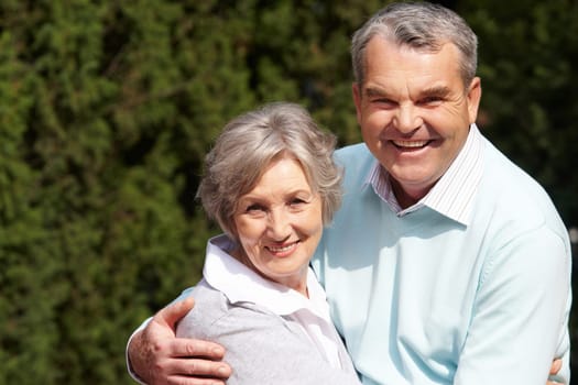 Portrait of happy senior couple embracing each other and looking at camera