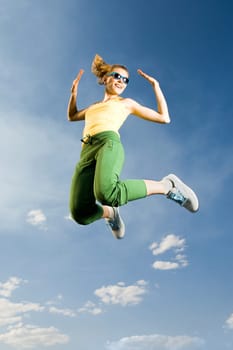 Image of cheerful girl in high jump against bright blue sky
