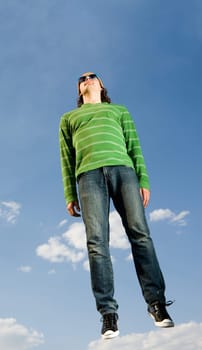 Portrait of casually dressed man in high jump against bright blue sky