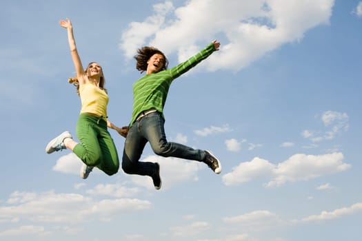 Image of cheerful girl and guy jumping high against bright blue sky and laughing