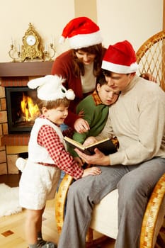 Portrait of family gathered together to read interesting fairy tale with fireplace behind