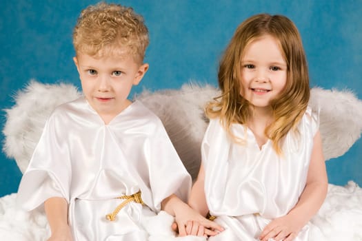 Portrait of two cute children wearing white silk clothing and looking at camera