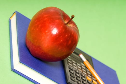 red apple and blue book and black calculator