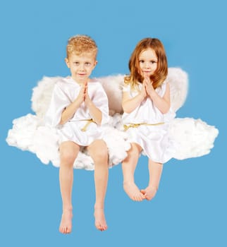 Portrait of two cute angels sitting on the cloud
