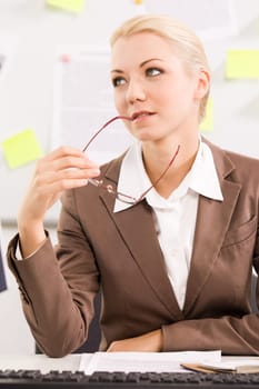 Portrait of pensive businesswoman sitting at workplace with eyeglasses in hand