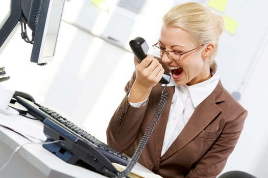 A young businesswoman shouting in telephone receiver
