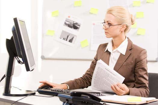 Pretty specialist looking at monitor of computer while sitting in office