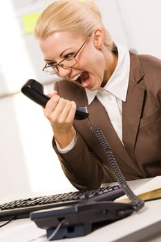 Portrait of secretary screaming in telephone receiver on working day