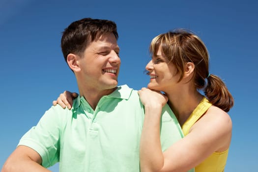 Photo of amorous couple smiling at each other while happy woman embracing her husband