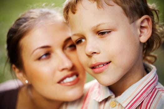 Close-up of a boys face and his mother looking at him in the background