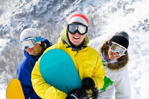 Portrait of three happy young men with snowboards in googles