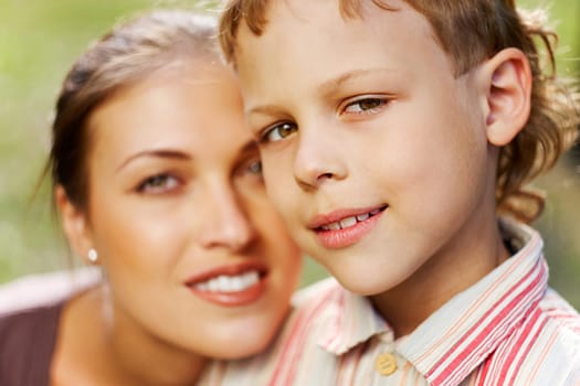 Portrait of handsome boy smiling at camera with his mother on background