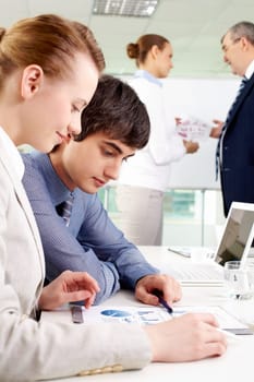 Portrait of confident man looking at document with female near by in working environment