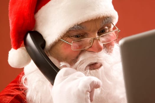 Photo of Santa Claus calling by phone and smiling