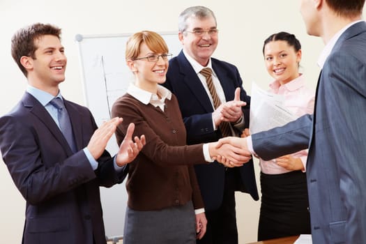 Photo of successful business partners handshaking after striking great deal with applauding people near by