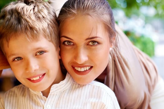 Portrait of handsome boy smiling at camera with his mother near by