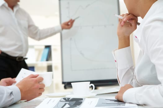 Photo of human hands over workplace on background of teacher by the whiteboard