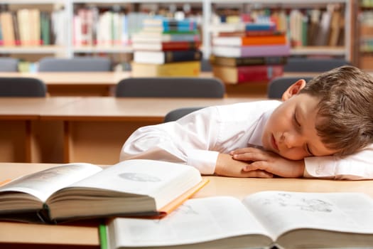 Image of young boy sleeping near books in the library