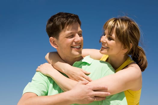 Photo of happy woman embracing her husband against bright blue sky