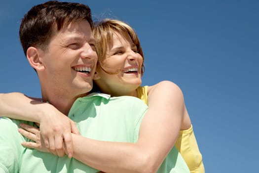 Photo of pretty female embracing happy man against bright blue sky