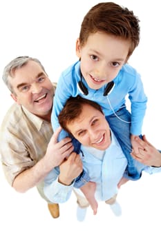 A boy sitting on his fathers shoulders with a grandfather standing by them
