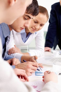 Portrait of confident man looking at document being discussed by co-workers