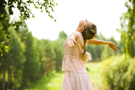 Photo of girl standing with her arms outstretched while taking pleasure in walk on summer day