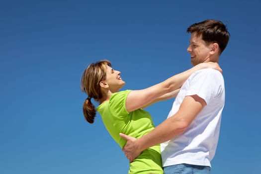 Photo of happy couple embracing against blue sky