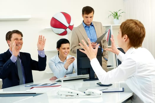 Businesspeople throwing basketball in the office