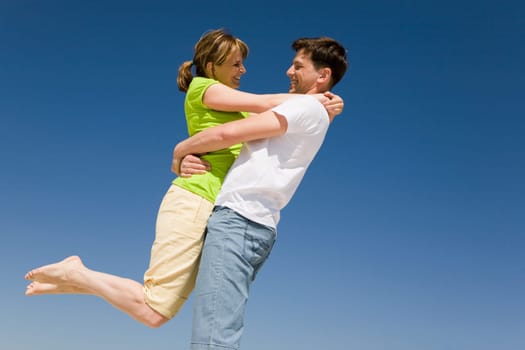 Photo of happy man holding his wife against bright blue sky
