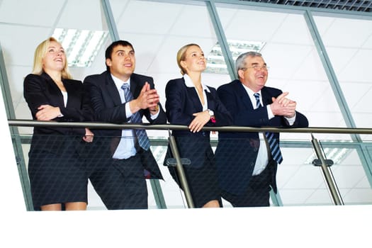Group of businesspeople and their senior boss standing by banisters