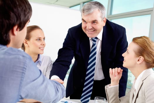 Photo of successful businessmen handshaking after striking deal with partners near by