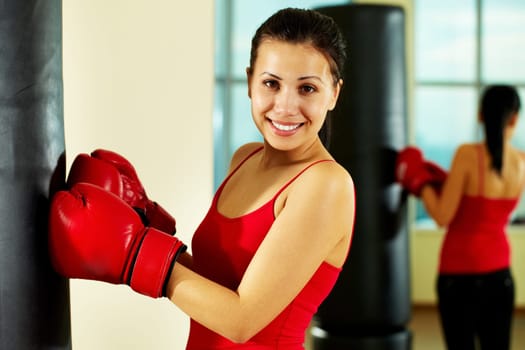 Portrait of young woman in red boxing gloves looking at camera