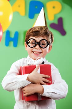 Portrait of happy lad in funny eyeglasses on birthday party with present