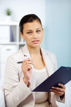 Portrait of smiling businesswoman with pen and clipboard looking at camera