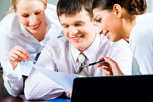 Portrait of a businessman looking at document with smile with two beautiful smiling business ladies near by