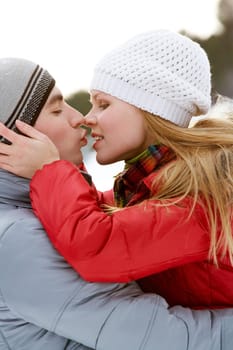 Portrait of happy couple kissing outdoors in winter