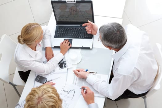 Above view of workteam discussing computer project at meeting