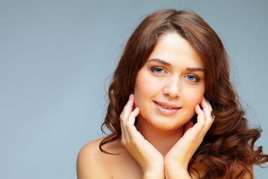 Portrait of charming girl looking at camera on grey background