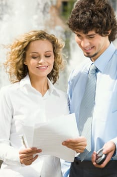 Portrait of two businesswomen  standing outside ahead of the fountain reading the contract