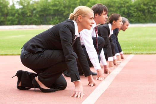 Row of business people looking attentively forwards before signal to run