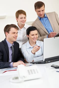 Portrait of business group looking at laptop screen in office